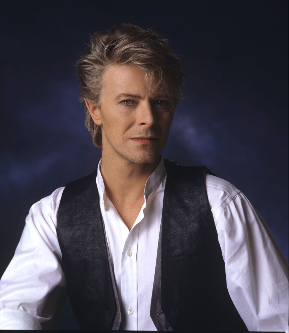 David Bowie in a white button-down shirt and black vest