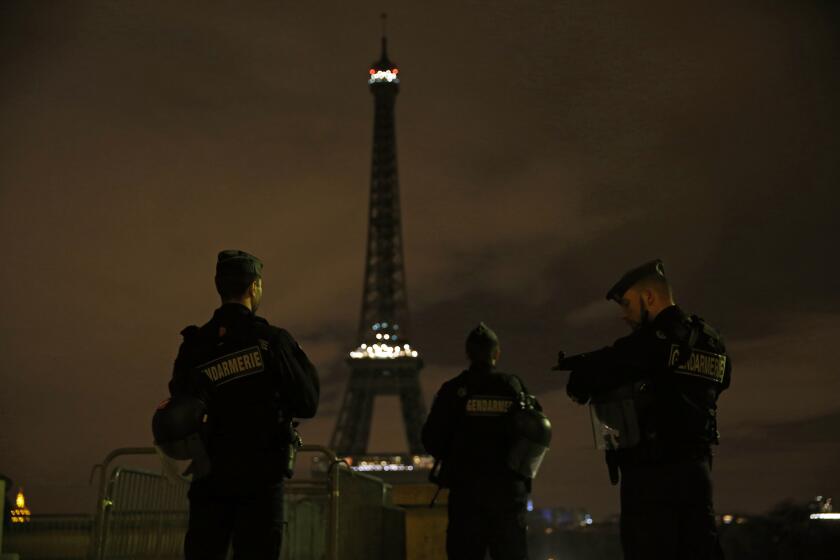 Armed police stand guard Nov. 14 near the Eiffel Tower, which was kept dark in honor of those who died in the terrorist attacks.