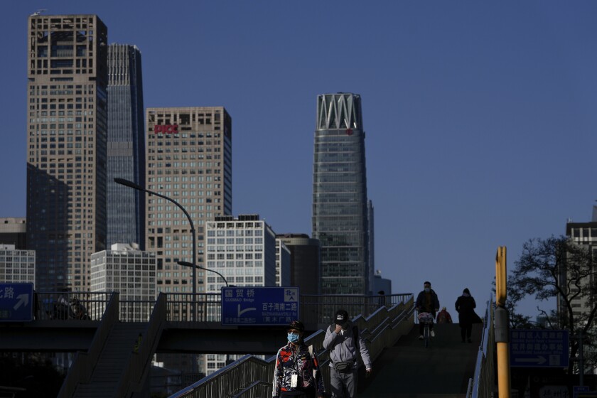 Masked pedestrians on a bridge with tall buildings in the background 
