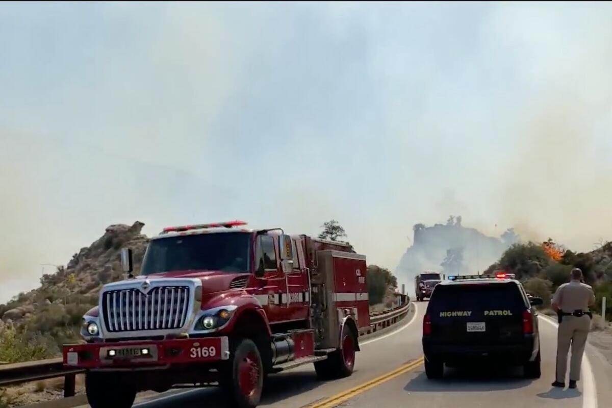 A fire truck and a police SUV with smoke in the background