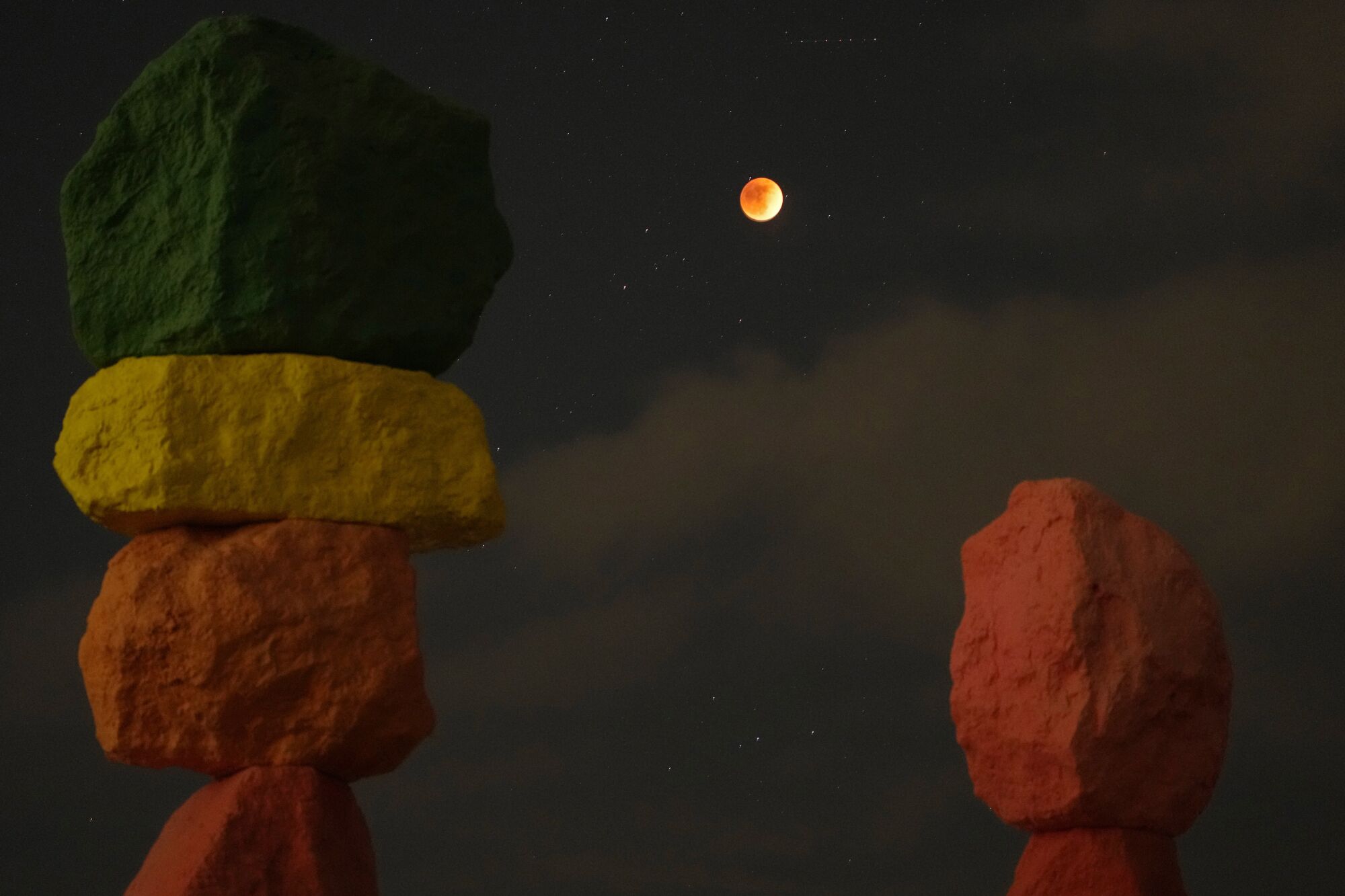Stacks of painted rocks next to an eclipsed full moon