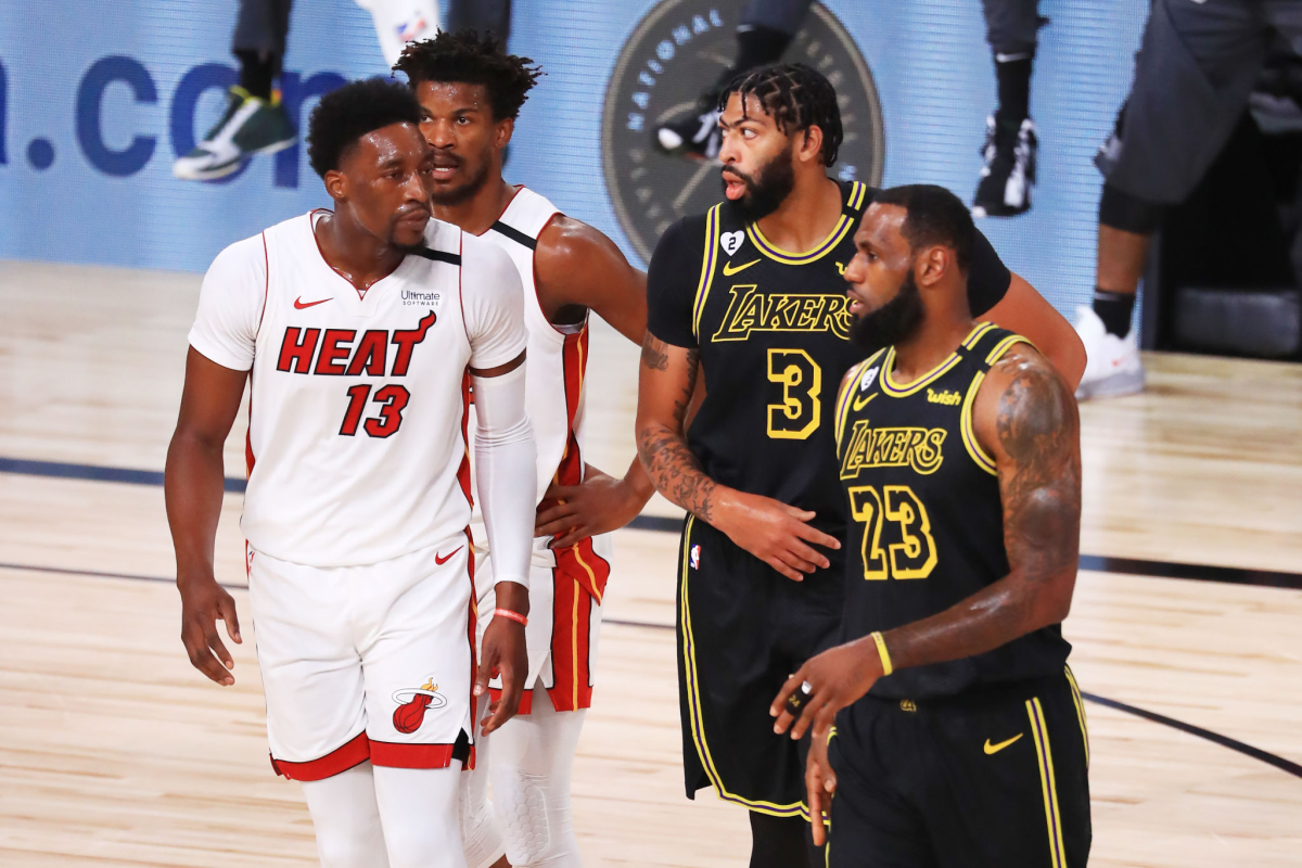 Lakers' LeBron James (23) and Anthony Davis (3) walk on court with Heat's Bam Adebayo (13) and Jimmy Butler (22).