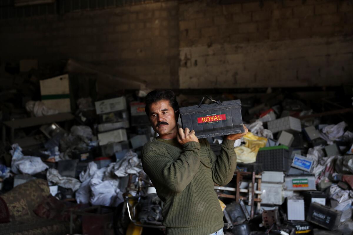 A Palestinian worker carries a discarded battery