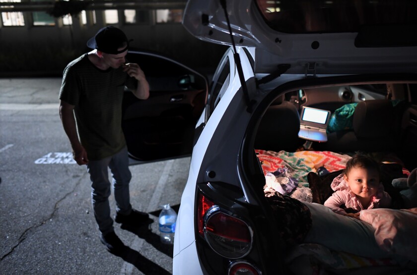 Jeremy Shriver brushes his teeth as he prepares for bed with his 19-month-old daughter Irah at a safe parking site in Los Angeles.