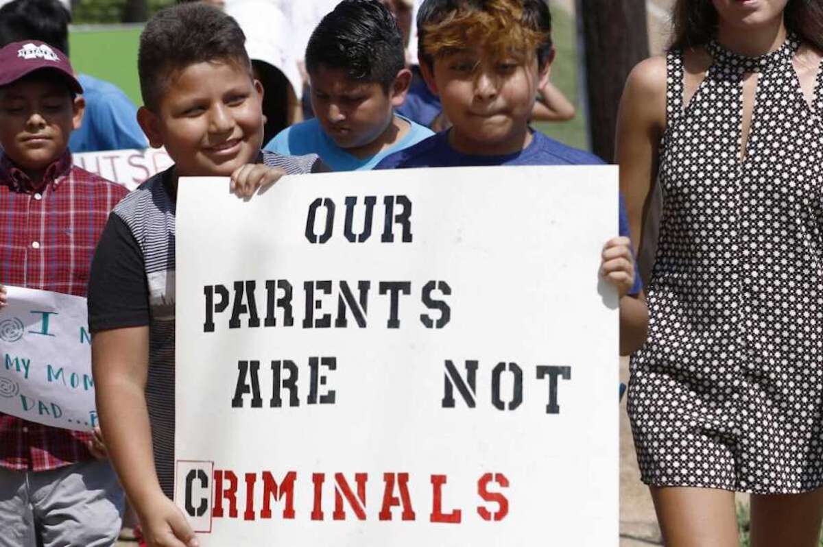 Menores hijos de padres latinos sostienen un cartel en apoyo a sus progenitores y de las personas arrestadas durante una redada contra migrantes no autorizados en una planta procesadora de carne, en Catón, Missouri. El letrero dice “Nuestros padres no son delincuentes”.