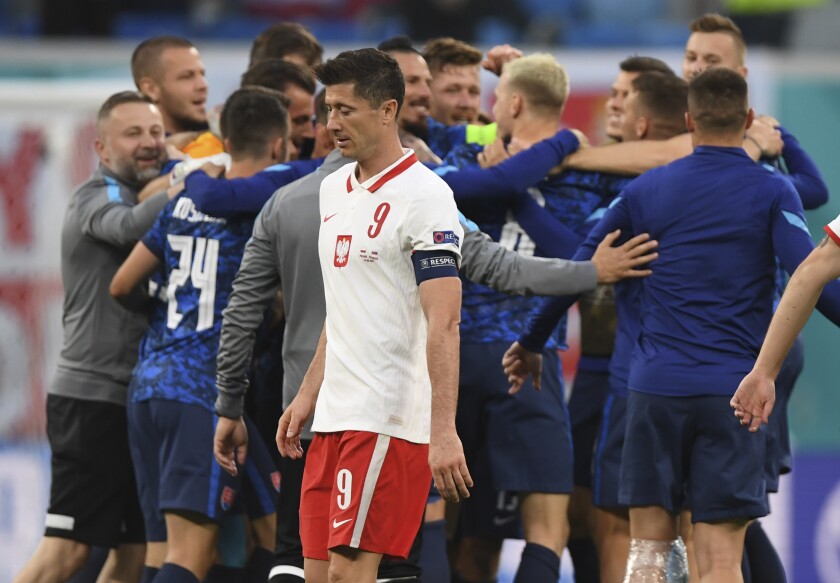 Poland's Robert Lewandowski, centre, walks as Slovakia players celebrate their victory after the Euro 2020 soccer championship group E match between Poland and Slovakia at Gazprom arena stadium in St. Petersburg, Russia, Monday, June 14, 2021. (Kirill Kudryavtsev/Pool via AP)