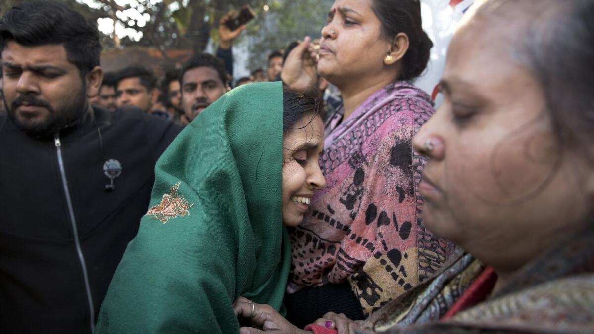 Relatives gather outside after an early morning fire killed more than a dozen people at a hotel in the Karol Bagh neighborhood of New Delhi on Tuesday, Feb. 12, 2019.