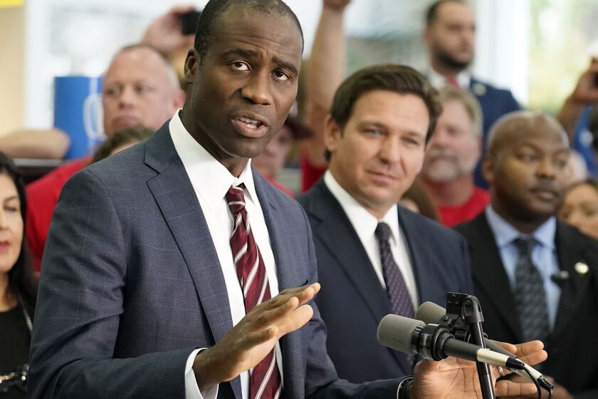 Florida Surgeon General Dr. Joseph Ladapo, front left, gestures before a bill signing by Gov. Ron DeSantis