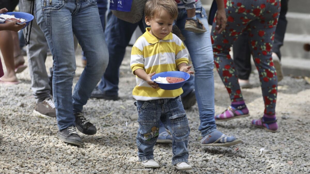 A boy walks to a nearby table with a plate of food at a migrant shelter near Cucuta, Colombia, on the border with Venezuela on Feb. 18, 2019. The shelter's director says they serve about 4,500 lunches per day, mostly to Venezuelan migrants.