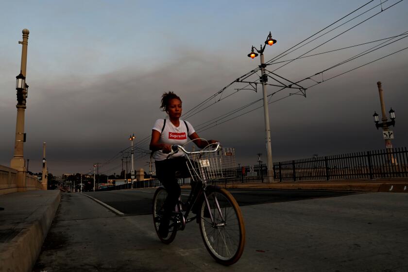 A bicyclist along the First Street Bridge as a layer of smoke hovers east of downtown in Los Angeles.