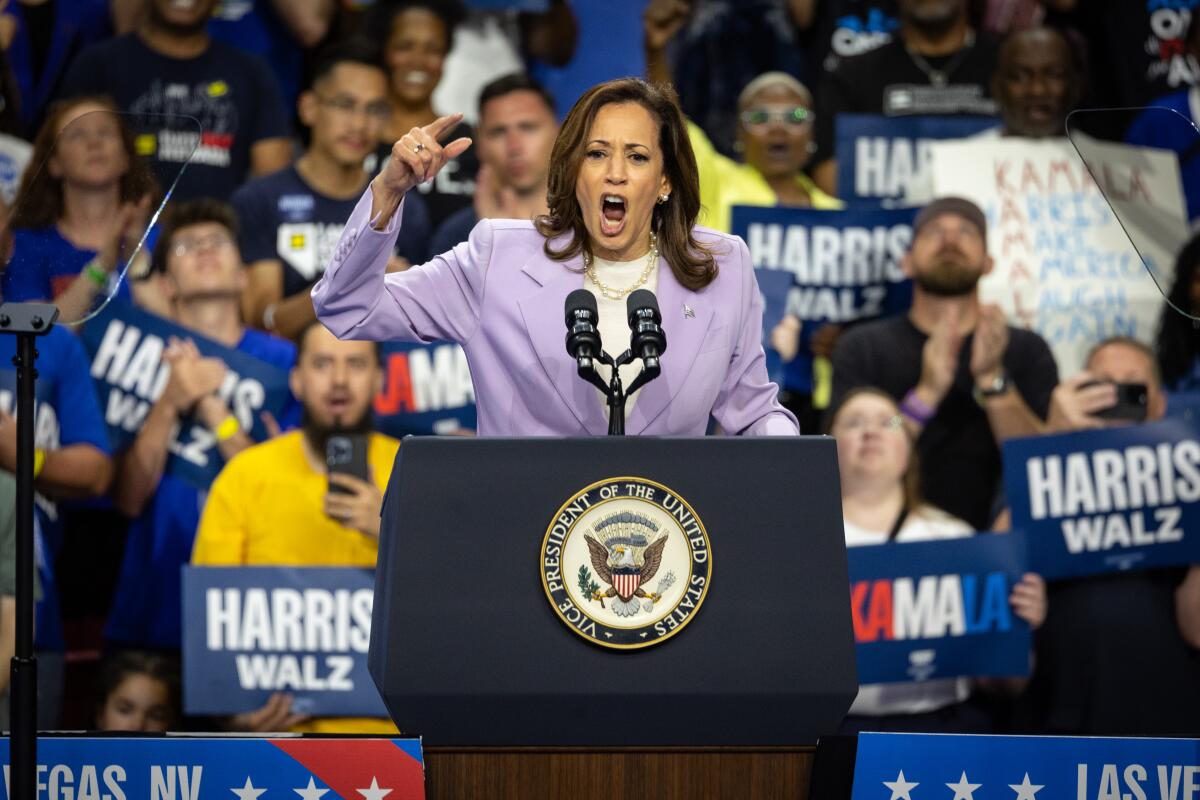 Kamala Harris, in a purple suit, speaks.