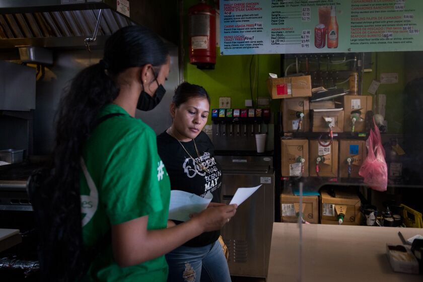Melissa Lopez explains the coronavirus testing process to a taco shop employee in Fresno.