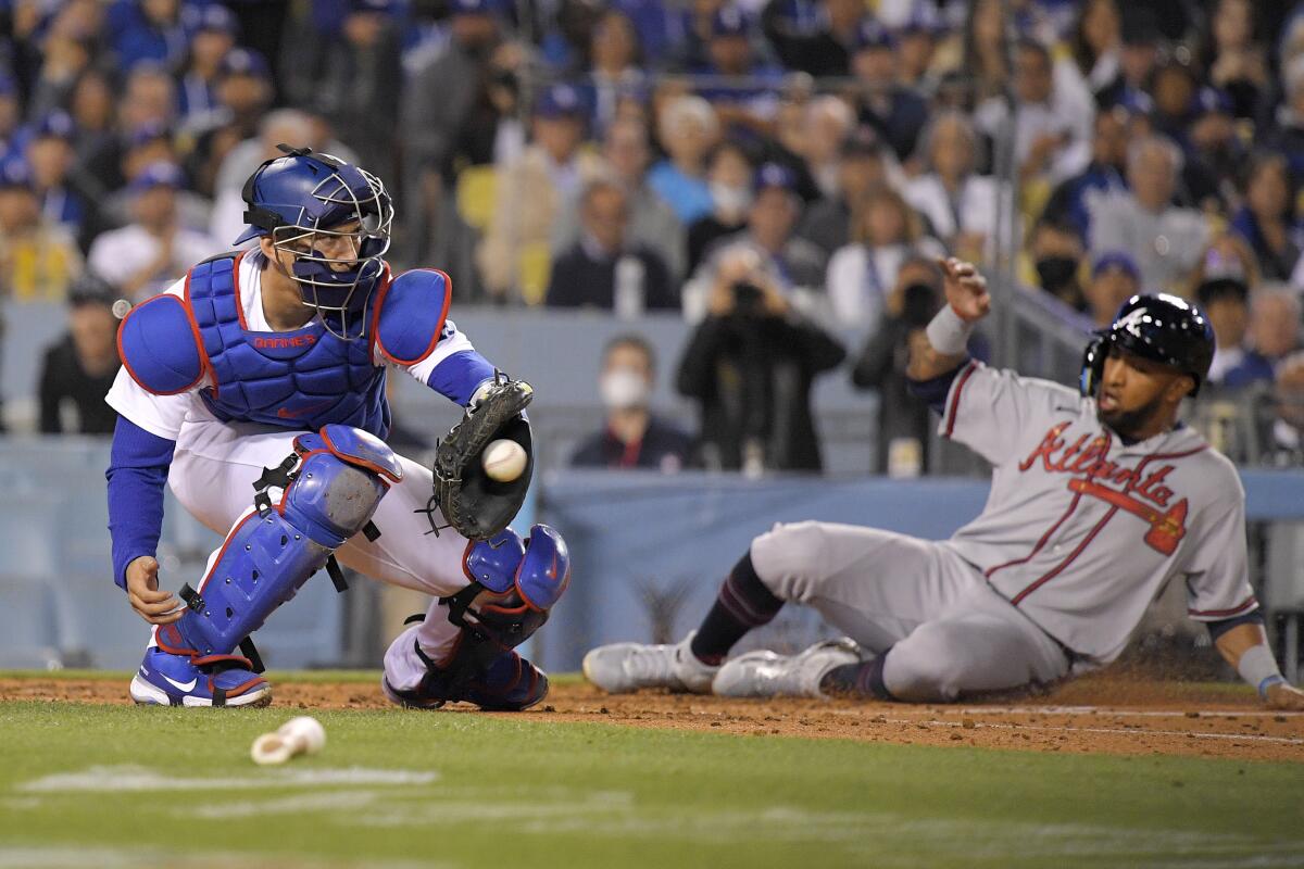 Atlanta Braves' Eddie Rosario scores on a double by Orlando Arcia as Dodgers catcher Austin Barnes takes a late throw.