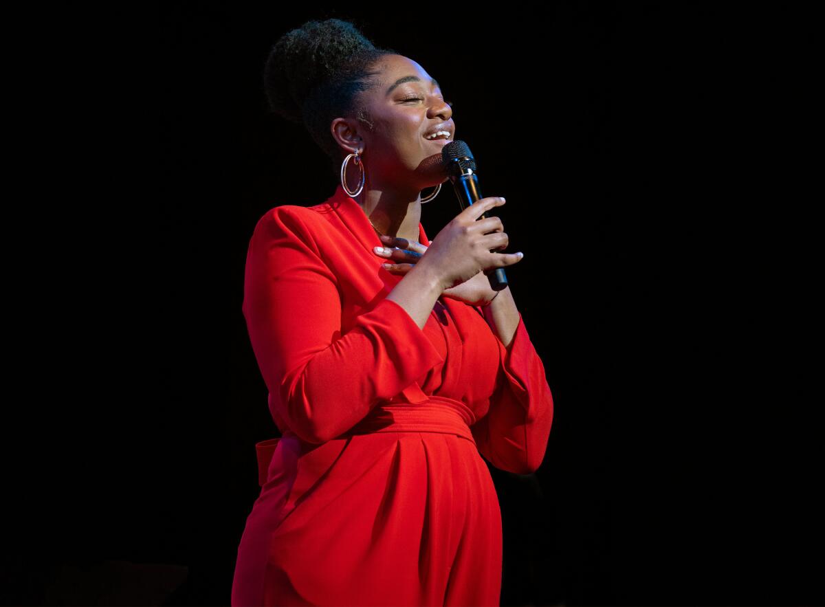 A woman in red singing into a mic.