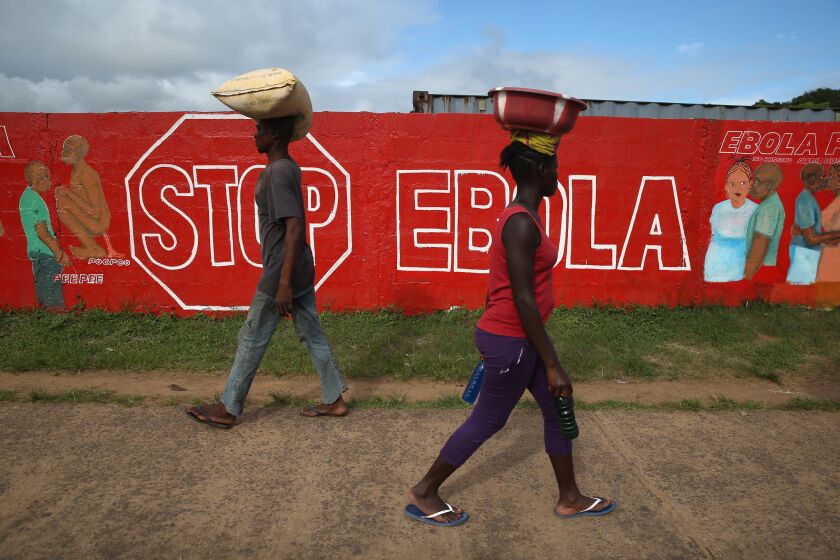 People pass an Ebola awareness mural on Thursday in Monrovia, Liberia.
