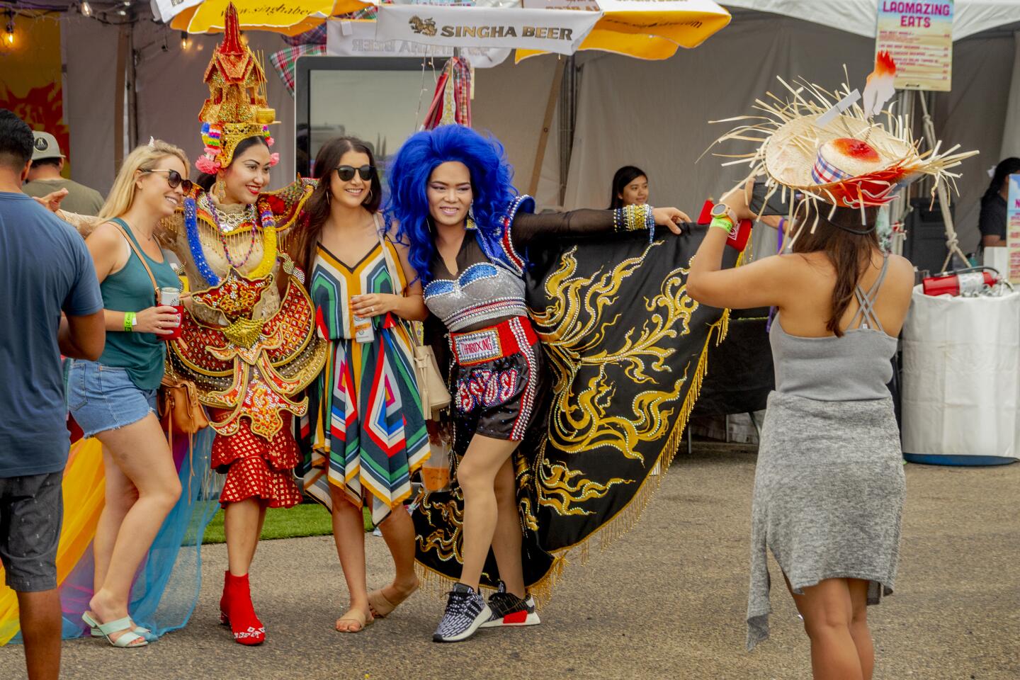 Boom Wanrisa, second from left in a Thai temple dress, joins Tatar Watcharin in her blue wig in posing with customers at Farmhouse Kitchen at the Nood Beach festival Sunday in Huntington Beach.