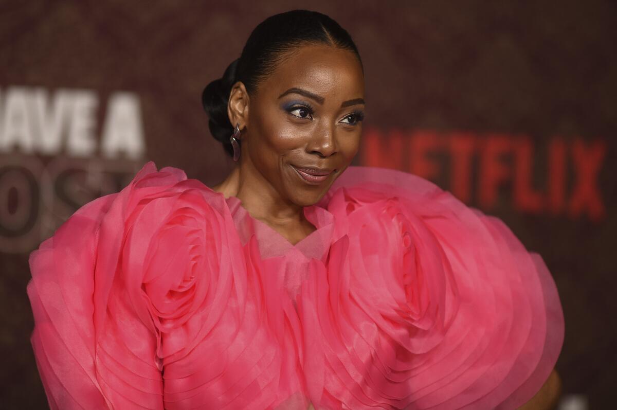 Erica Ash smiling in a a voluminous ruffled pink gown with her hair pinned up