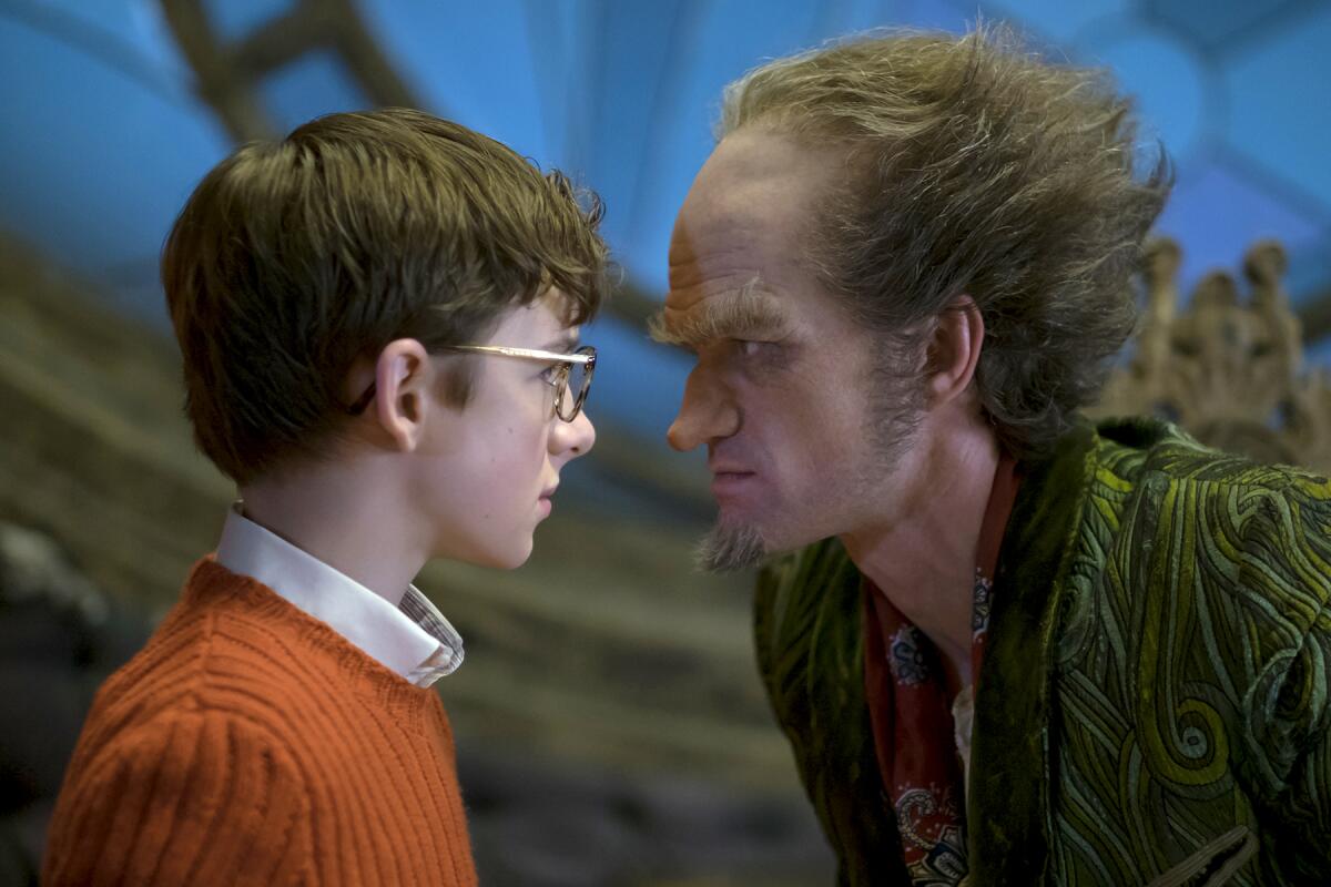 A young bespectacled boy and an older man stand face to mean face.