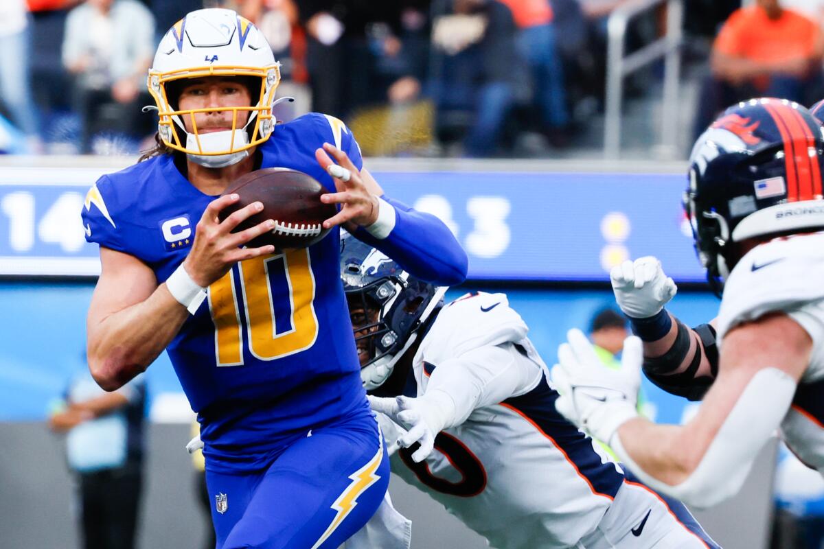 Chargers quarterback Justin Herbert tries to scramble away from Denver Broncos linebacker Jonathon Cooper in the first half.