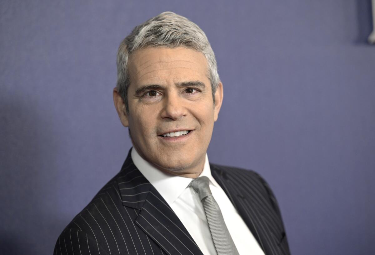 A man with gray hair posing in a black pinstripe suit and gray tie.