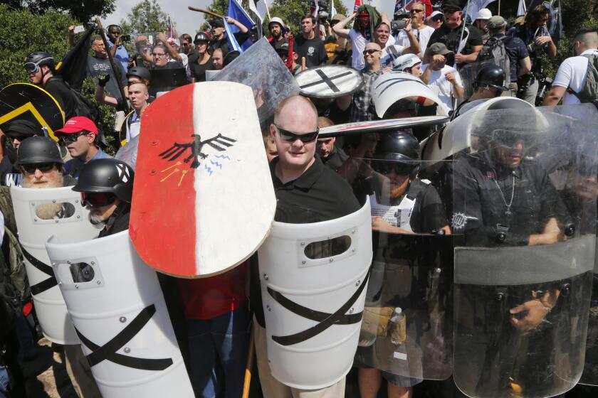 White nationalist demonstrators use shields as they guard the entrance to Lee Park in Charlottesville, Va.