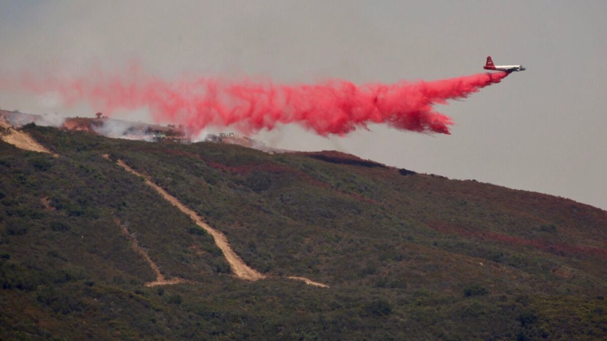 A plane drops red fire retardant on a wildfire