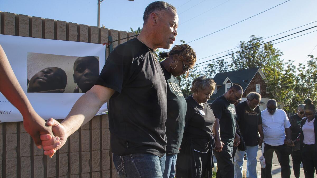 Pastor Joshua Beckley of Ecclesia Christian Fellowship leads community members in prayer at a memorial for shooting victim Jason Spears, 12, who was shot while buying a bag of chips.