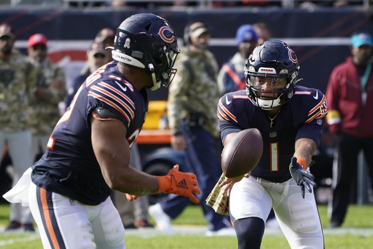 Chicago Bears quarterback Justin Fields (1) tosses the ball out to running back David Montgomery during the first half of an NFL football game against the Baltimore Ravens Sunday, Nov. 21, 2021, in Chicago. (AP Photo/Charles Rex Arbogast)