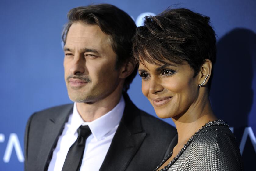 Halle Berry, wearing a silver dress is posing with her ex-husband Olivier Martinez as the pair smile for cameras 