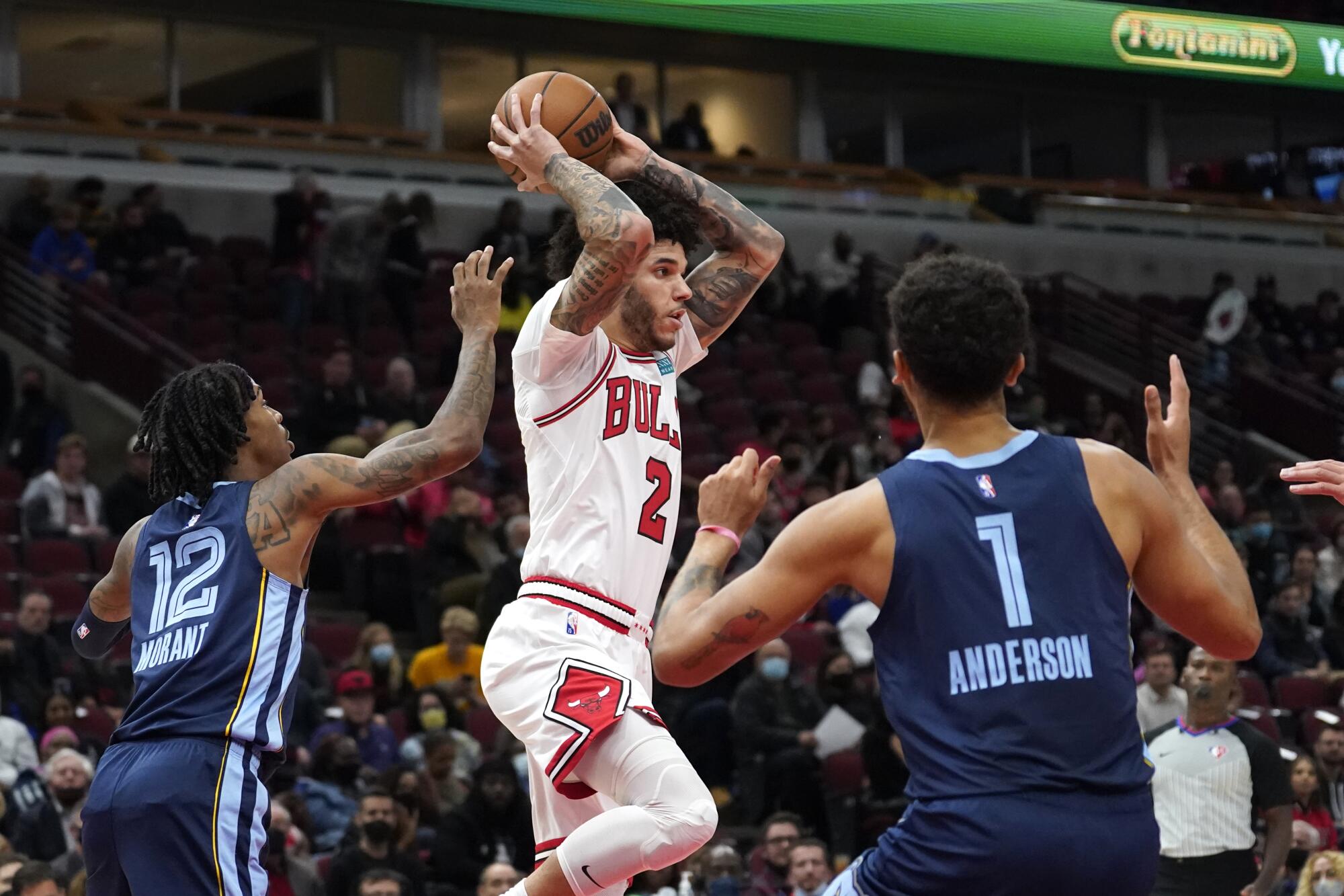 The Bulls' Lonzo Ball makes a pass while under pressure from Grizzlies guard Ja Morant, left, and forward Kyle Anderson.