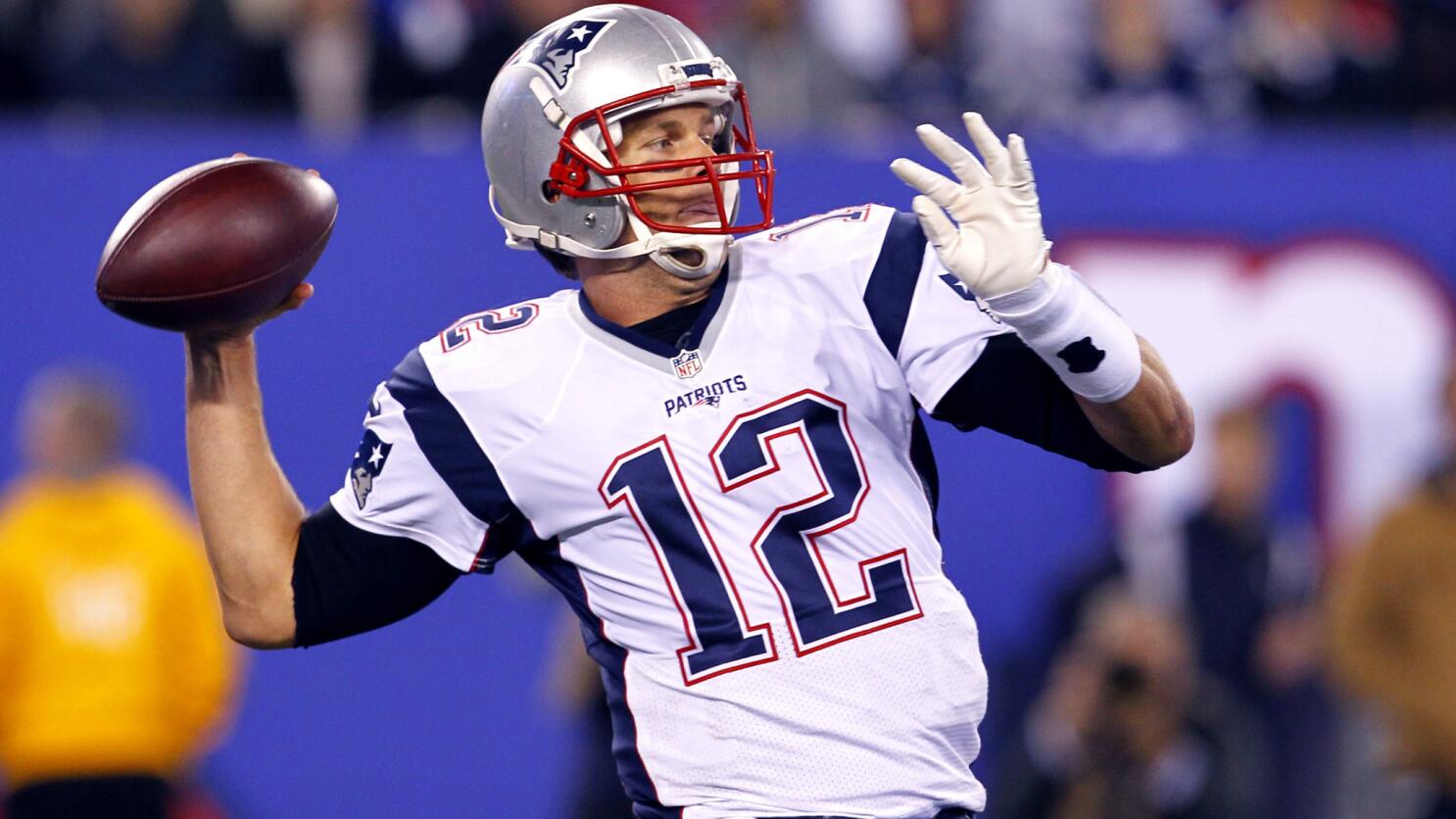 New England Patriots quarterback Tom Brady smiles while walking on