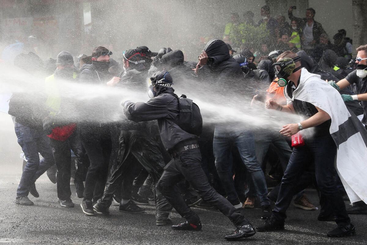 Masked protestors are sprayed with water cannons during clashes with police during annual May Day rally in Paris. (KENZO TRIBOUILLARD / AFP / Getty Images)