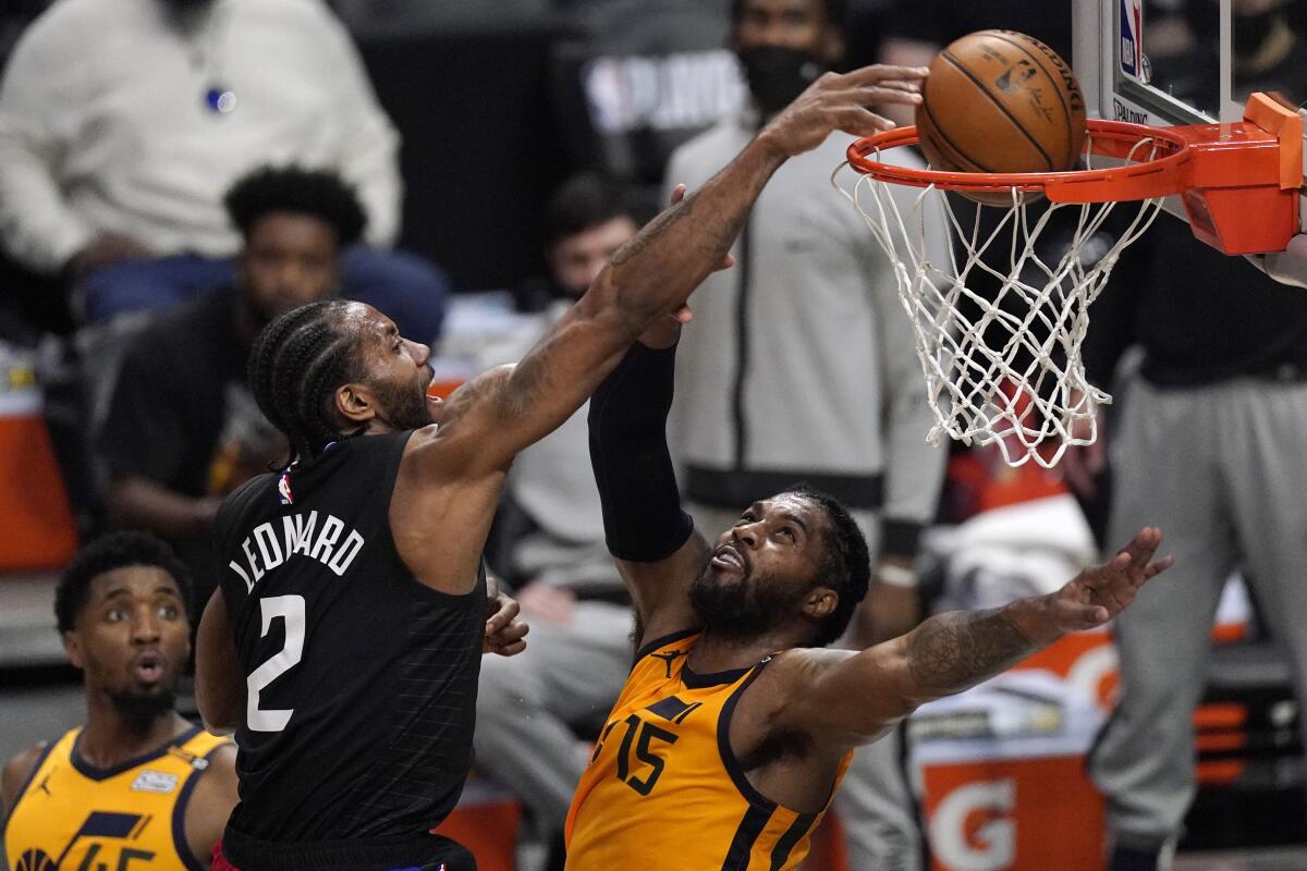El jugador de los Clippers de Los Ángeles Kawhi Leonard, en el centro, hace una clavada por encima del jugador del Jazz.