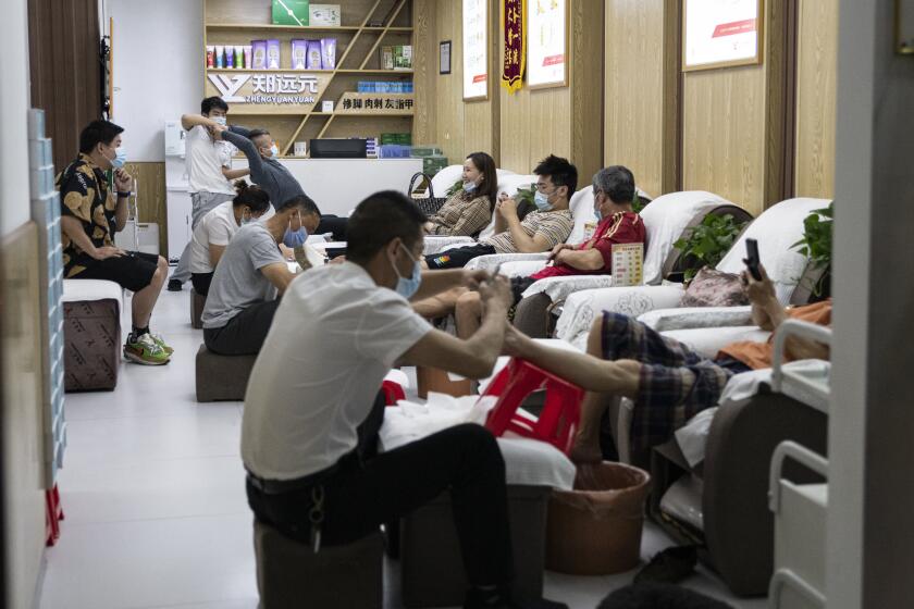 Wuhan people do massage with protective mask in a massage parlor.