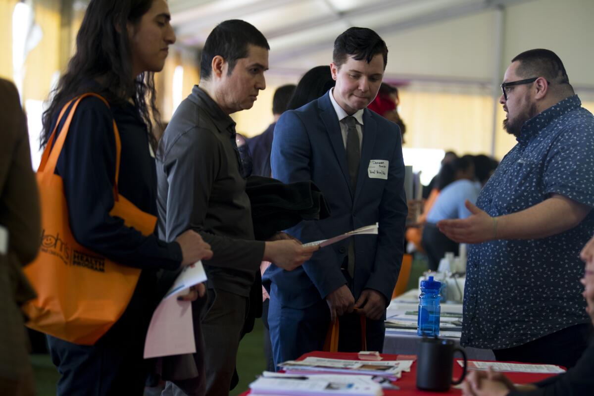 Donovan Smith, 21, middle, speaks with George Luna-Peña, right, manager for the Diversity Apprentice Program at The Broad during the St. John's Well Child and Family Center's job fair for Los Angeles' transgender community at Trade Tech College in Los Angeles in March.
