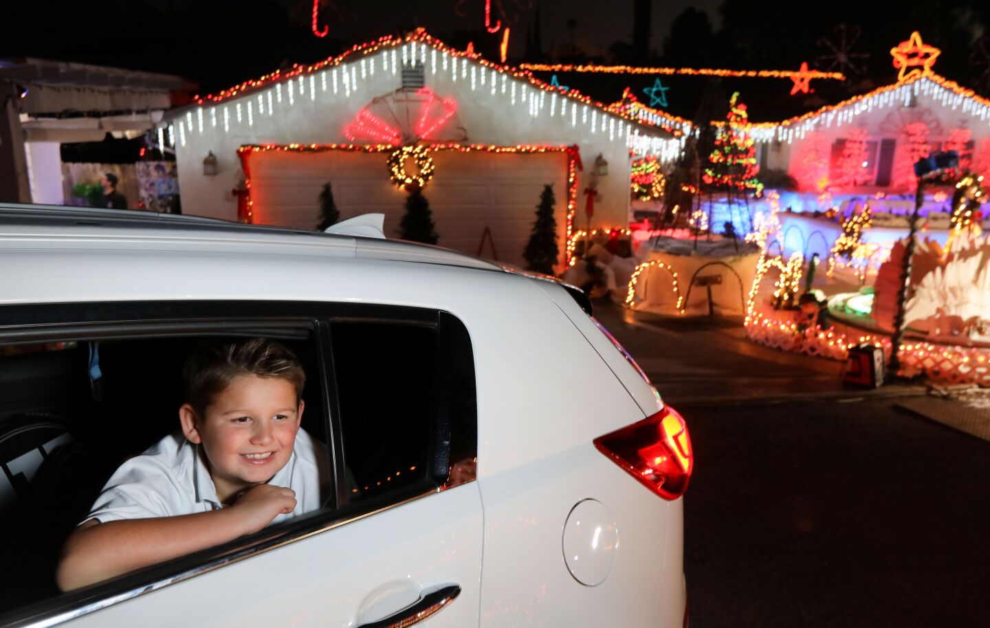 Eight-year-old Logan Taylor enjoys the extensive Christmas decorations on both side of the circular driveway of the home of Mack Schreiber on Reche Road in Fallbrook. A steady stream of vehicles pass through.
