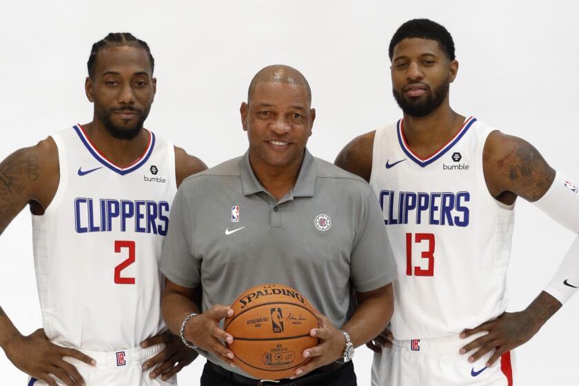 Clippers forwards Kawhi Leonard (2) and Paul George (13) flank coach Doc Rivers during a photo shoot on media day.