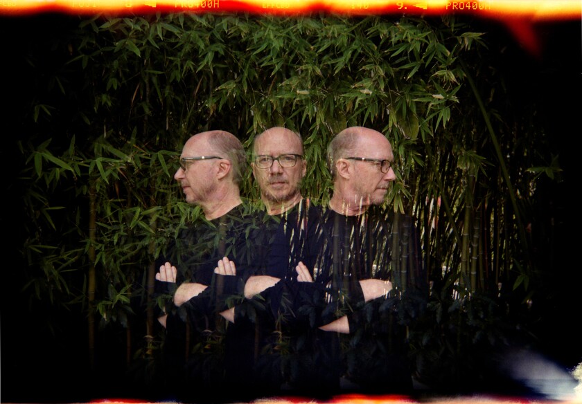 A triple-exposure photo of a man with his arms crossed looking forward, to the left and to the right 
