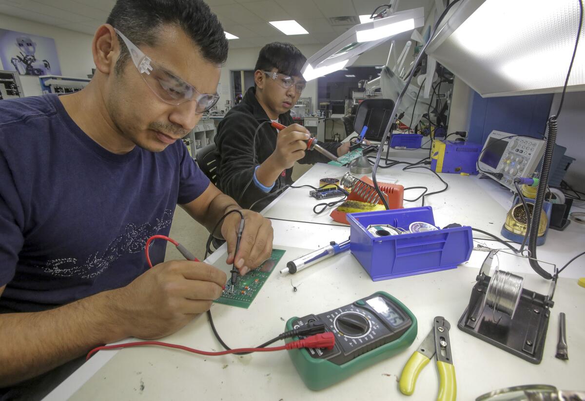 Students Jorge Arellano, left, and Henzel Florendo work on circuit boards Friday at MiraCosta College.