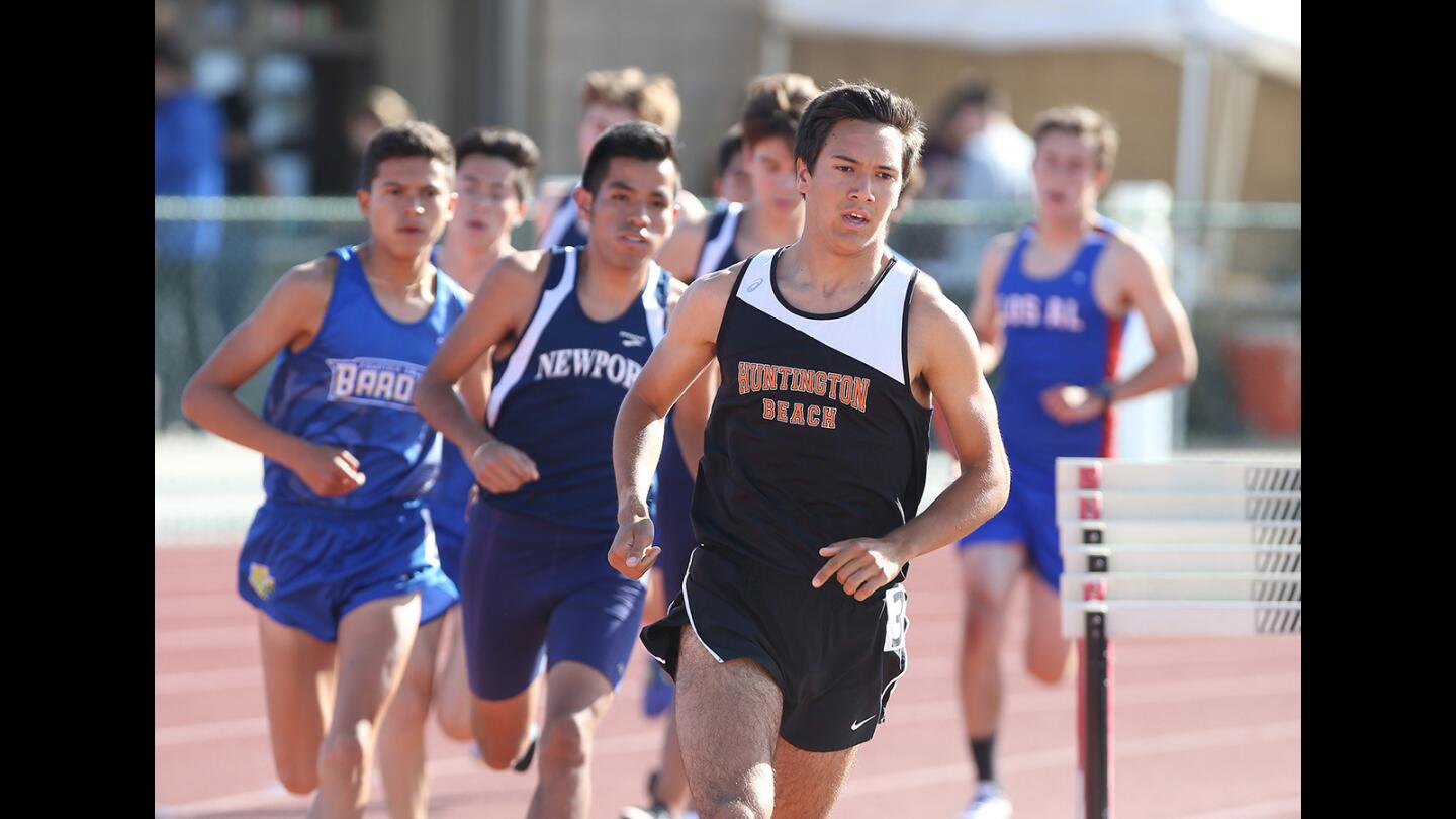 Huntington Beach High's Mitchel Lars rounds the last turn with Newport Harbor's Alexis Garcia, in the boys' varsity 1600 meter run during the Sunset League track finals at Westminster High on Friday. Newport's