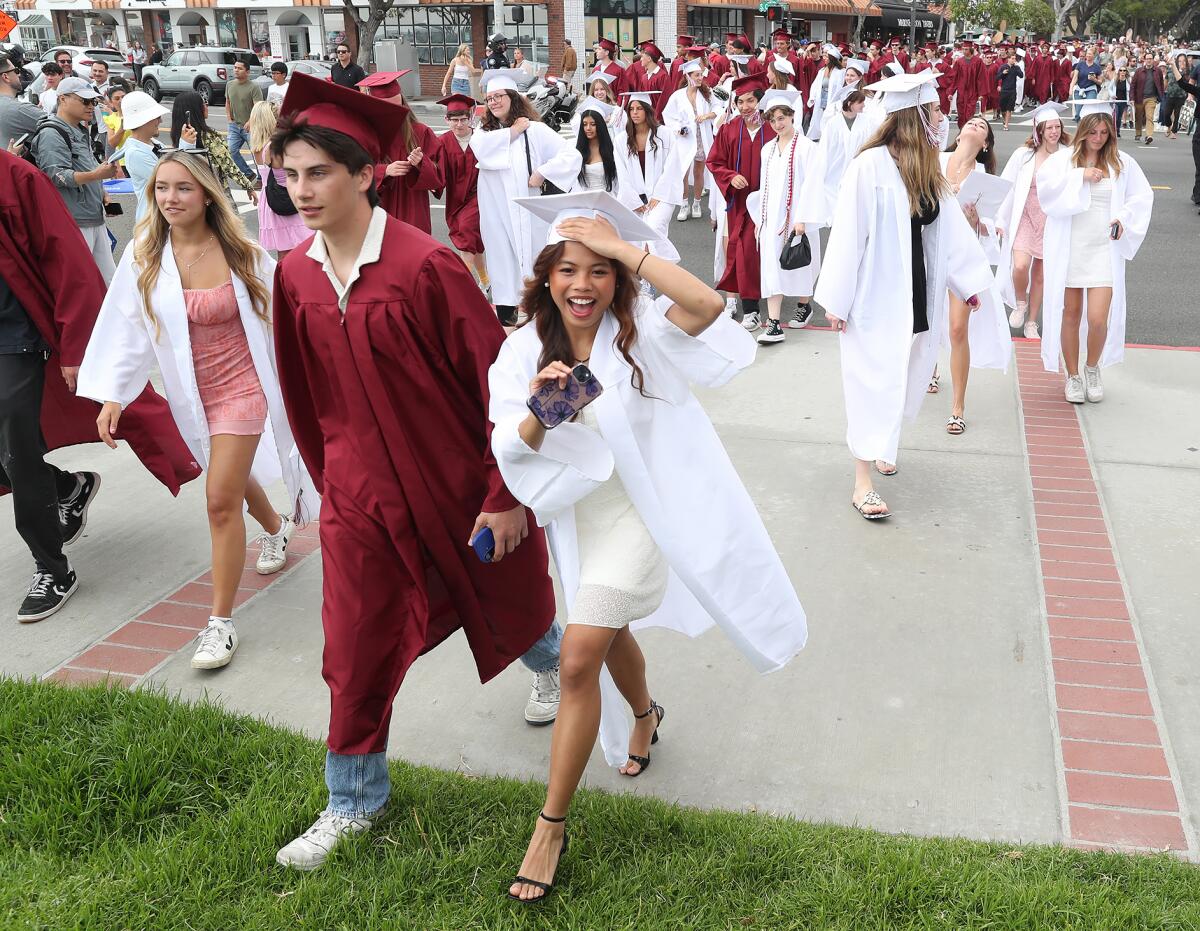 Laguna Beach High seniors happily step across the sidewalk to Main Beach Park as they participate in a downtown parade.
