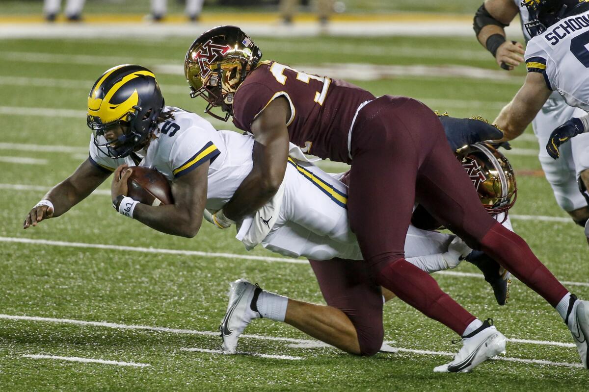 Michigan quarterback Joe Milton dives forward as Minnesota defensive lineman Boye Mafe tackles him Oct. 24, 2020.