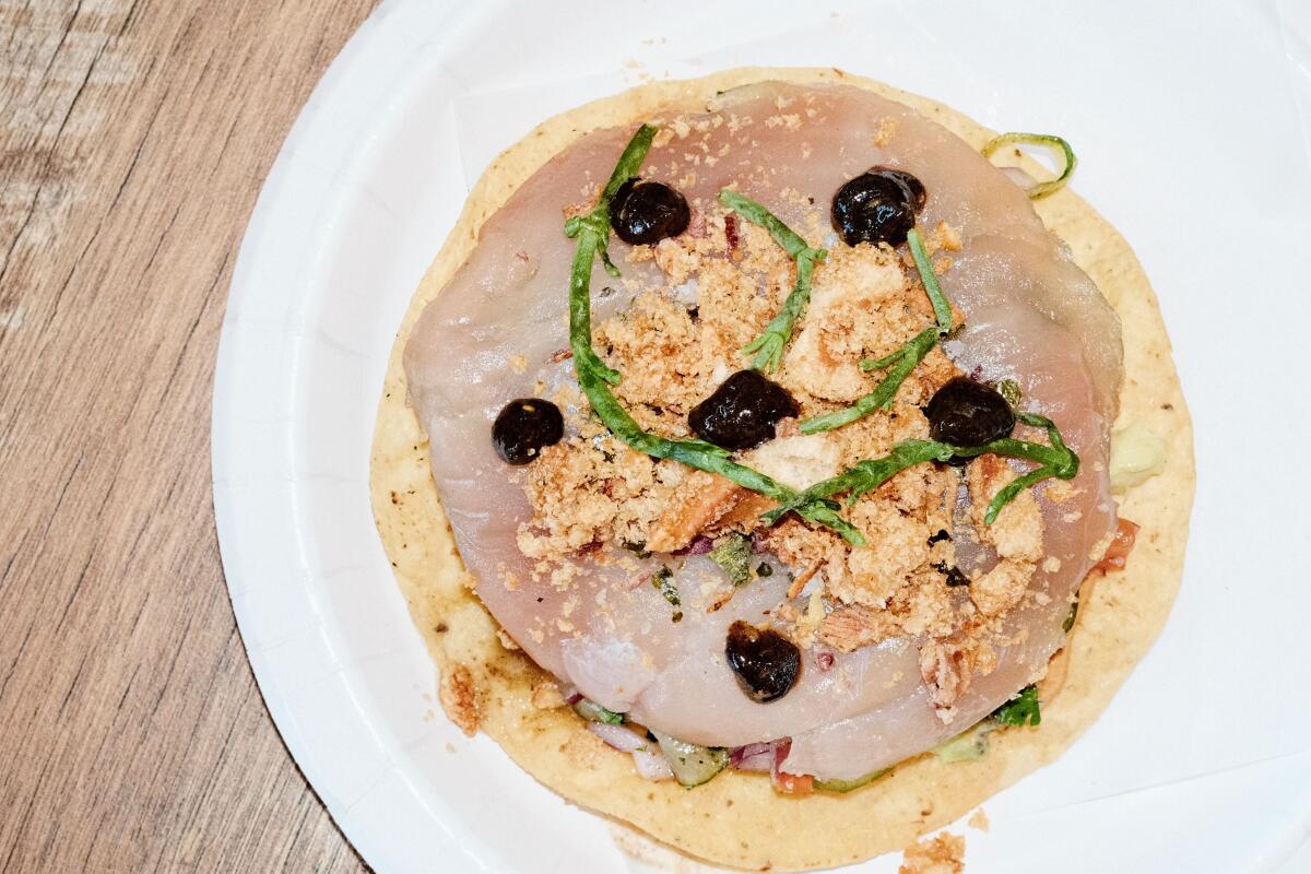 An albacore tostada topped with sea beans and sesame salsa on a white paper plate at Three Flames in Westchester
