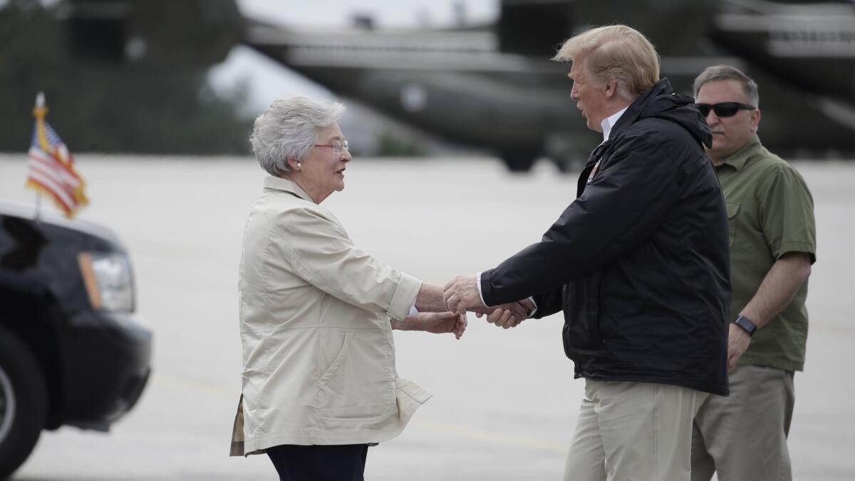President Trump is greeted by Gov. Kay Ivey in Auburn, Ala., en route to Lee County, where a tornado killed 23 people.