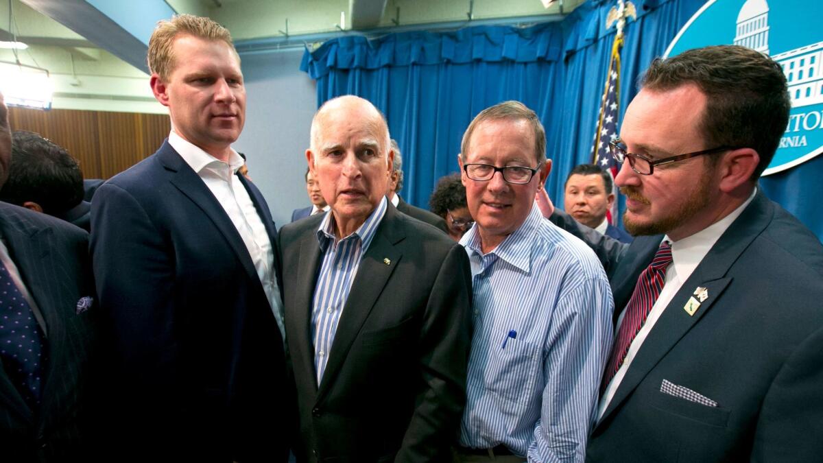 Gov. Jerry Brown is flanked by Assembly Republicans Chad Mayes, left, Tom Berryhill and Devon Mathis as he leaves a news conference after the Legislature approved a pair of climate change bills.