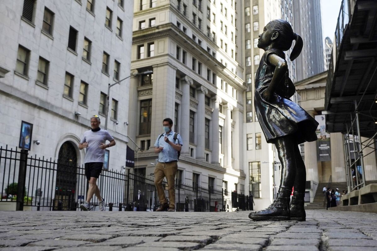FILE - In this June 16, 2021, photo, the "Fearless Girl" statue faces the New York Stock Exchange. The 4-foot bronze "Fearless Girl" statue that was installed opposite New York City's Charging Bull in 2017 will remain in its current spot opposite the New York Stock Exchange at least until early 2023 while city officials wrestle with a permanent disposition for the popular symbol of female empowerment, a city board decided Monday, April 11, 2022. (AP Photo/Richard Drew, File)