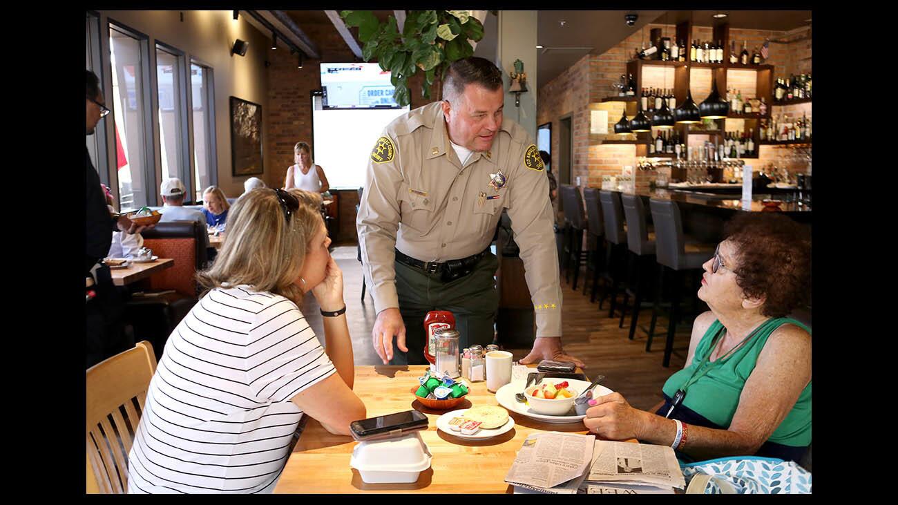 L.A. County Crescenta Valley Sheriff station captain Christopher M. Blasnek speaks with La Canada Flintridge resident Harriet Hammons, right, as Heidi Moreno looks on, left, during the annual Tip A Cop event at Hill Street Cafe, in La Canada Flintridge on Friday, Aug. 17, 2018. The fundraiser helps the Special Olympics torch run.