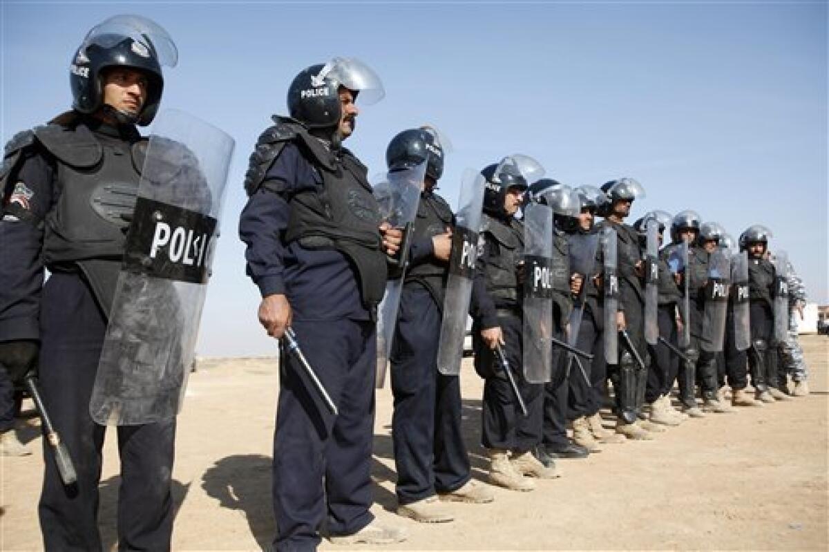 Iraqi Police in riot gear stand in formation during a government-sponsored media trip to Camp Ashraf, which houses Iranian exiles near the border with Iran, north of Baghdad, Iraq, Tuesday, Dec. 15, 2009. The Iranian opposition group, the People's Mujahedeen Organization of Iran, was hosted in Iraq for years by former Iraqi dictator Saddam Hussein, a reflection of the tense relations between the two countries.Iraq has announced plans to move the group's members, now living at Camp Ashraf, to a former desert detention camp. (AP Photo/ Hadi Mizban)