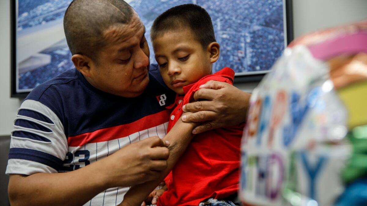 Guatemalan asylum seeker Hermelindo Che Coc inspects his 6-year-old son after reuniting last July after two months of separation that occurred when they crossed the border from Mexico.