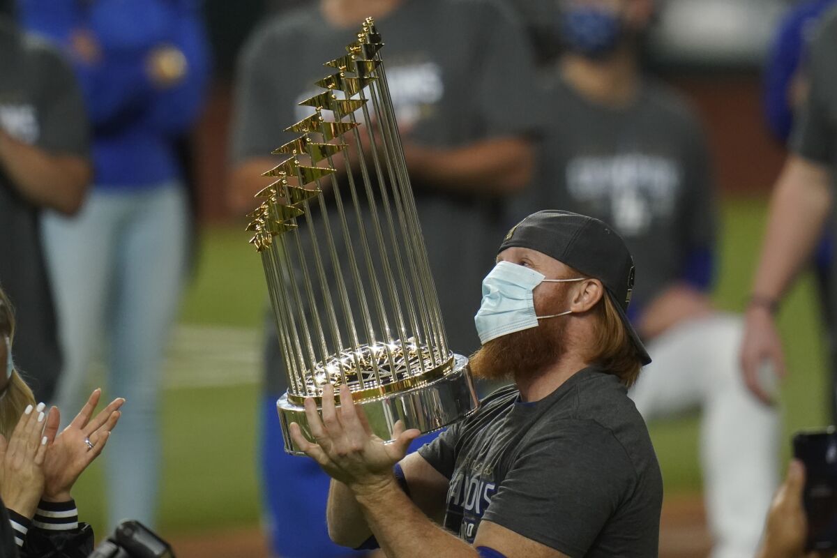 FILE - In this Tuesday, Oct. 27, 2020, file photo, Los Angeles Dodgers third baseman Justin Turner celebrates with the trophy after defeating the Tampa Bay Rays 3-1 to win the baseball World Series in Game 6 in Arlington, Texas. Baseball nearly made it through its version of playoff bubbles unscathed; two innings before the World Series ended, Justin Turner of the now-champion Los Angeles Dodgers Turner was pulled from the game after MLB was notified that he had tested positive for COVID-19. (AP Photo/Eric Gay, File)